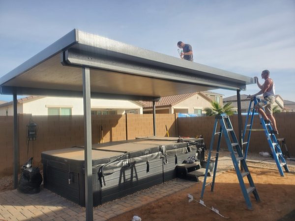 City Seamless crew installing a dark aluminum patio cover for Las Vegas area homeowners.